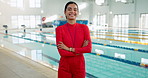 Woman, swimming coach and happy in indoor aquatic center, arms crossed and confident for lesson. Female person, trainer and instructor as teacher with smile, whistle and ready for session by pool