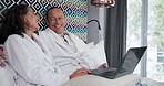 Couple, laptop and talking on bed in hotel with laughing, comedy movie or watching funny video in robes. People, happy and technology in bedroom of accommodation for relax, holiday and conversation