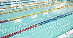 Indoor, empty and swimming pool for professional sport, health and competition with window reflection. Calm, lane dividers and water for aquatic activity with exercise, workout and race event in gym