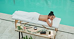 Hotel, aromatherapy and woman with massage on table for self care, treatment and spa service. Top view, female client and relax with peace by pool for candle scent, healing and support in wellness