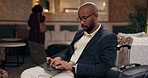 Businessman, laptop and suitcase for travel in first class lounge for networking, email and connection. Black, male person and tech in typing for meeting as international relations officer in airport