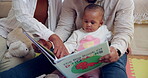 Baby, book and reading in living room with family for development or education in home. Child, mom and dad on floor for story, motor skills and fantasy or support on weekend in apartment or lounge