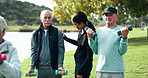 Fitness, dumbbells and senior men in park with help, personal trainer and wellness in muscle training. Physio, woman and group of elderly friends on grass for workout, stretching or mobility exercise