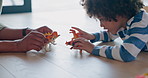 Father, son and playing with toy dinosours on floor for fun bonding, holiday or weekend at home. Hands of dad and little boy enjoying family time, pretend or dino fight in childhood together at house