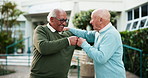 Senior men, fist bump and conversation in retirement home as friends, talking and agreement as partner. Elderly people, happy and cheerful in outdoor of nursing village with discussion, chat or unity