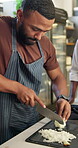 Culinary, man and knife with onion for cut, chop and food preparation technique for fine dining on table. Kitchen, learning and trainee chef with raw vegetable, hospitality or helping hand for skills