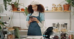 Coffee shop, woman and smile as waiters on smartphone for social media and communication. Small business, cashier and happy on counter for online order, ecommerce and networking at cafe or store