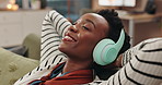 Black woman, headphones and relax on couch with smile, listening and music with streaming in home living room. Person, happy and excited for subscription, audio and relief on sofa with peace in house