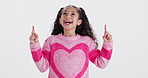 Pointing up, excited and face of child in studio for promotion, bargain and discount news on white background. Happy, fashion and portrait of isolated young girl with hand gesture for announcement