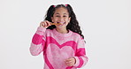 Girl, child and brushing teeth in studio, happy and face for hygiene, wellness and oral health by white background. Kid, bamboo toothbrush and smile for cleaning mouth with sustainable product