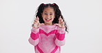 Wish, fingers crossed and face of child in studio for luck, hope and good news on white background. Excited, hopeful and isolated young girl with emoji, sign and hand gesture for winning prize