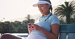 Tennis player, woman and break with phone on court for text message, communication or social media scroll. Sports, athlete and relax on bench with online fitness app, game research and mobile chat