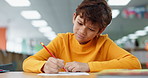 Kid, education and writing at library in school with notebook for assessment or assignment. Boy, studying and problem solving with stationery for project for child growth and brain development
