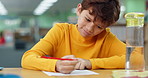 Boy, studying and happy in library at school with notebook for writing notes and exam preparation. Kid, education and smile with stationery for project for child growth and brain development