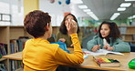 Hand, back and kid with answer in library for studying, help and academic support at school. Student, learning and people with response at desk for homework evaluation, education and tutor assistance