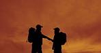 Handshake, hiking and orange sky with silhouette of friends outdoor in nature for adventure or bonding. Fist bump, high five and sunset with hiker people in environment together for team building