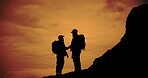 Handshake, hiking and orange sky with silhouette of friends outdoor in nature for adventure or bonding. Success, support and sunset with hiker people shaking hands in mountain environment together