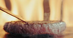 Fire, patty and spatula for burger with person in restaurant, cooking beef for cuisine, gourmet or meal. Flame, food and grill heat with chef in kitchen for preparation of take away order closeup