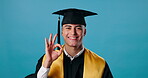 Man, happy and ok sign for graduation, celebration and achievement in school or education in studio. Graduate, face and award for university, college and certificate with success on blue background