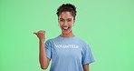 Pointing, smile and woman volunteer by green screen for announcement with ngo business. Happy, portrait and female charity worker with deictic hand gesture for marketing presentation by chroma key.