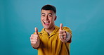 Thumbs up, excited and portrait of man in studio with positive attitude, like and happy vote. Thank you, smile and person with yes hand gesture for success, emoji and agreement on blue background