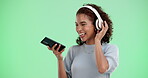 Woman, dance and green screen or headphone with smartphone, streaming and energy movement in studio. Happiness, track and audio listening on tech with connection, online and good mood on mobile app
