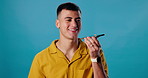 Happy man, talking and speaker with phone for audio message or recording in studio on a blue background. Male person or model with smile on mobile smartphone for voice note, app or sound notification