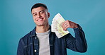 Face, smile and man with cash, finance and confident person on blue studio background. Portrait, guy and model with money, bonus and savings with investment, economy and salary increase with profit