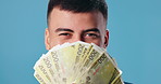 Face, bonus and man with cash, finance and confident person on blue studio background. Portrait, guy and model with money, profit and savings with investment, economy and salary increase with budget