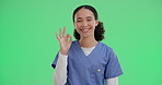 Nurse, face and green screen with okay in studio for health insurance, encouragement and care quality. Woman, happy and hand gesture or like sign for assurance of treatment success and wellness.