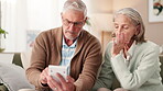 Senior couple, home and stress with calculator in living room for finances on water or electricity bills. People, relationship and argument with invoice for bank loan or mortgage and interest rate