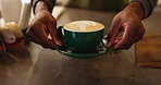 Hands, latte art and barista in coffee shop for hospitality or service closeup at counter. Retail, serving and small business with cafe employee in restaurant for presentation of beverage or drink