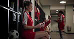 Phone, soccer player or woman in locker room for game, competition or texting in online chat. Social media news, football career and female athlete ready to start match or sports practice for fitness