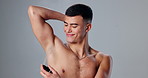 Studio, smile and man with deodorant, armpit and body care with confidence, protection and clean skin. Skincare, health and happy male model with spray, underarm product or hygiene on grey background