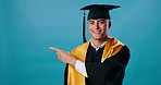 Man, graduate and pointing in studio mockup for list, career opportunity and options with smile. Student, decision and gesture on blue background space for choices, job offers or additional education