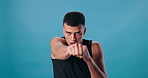 Man, face and boxer punching in studio, martial arts and energy for challenge on blue background. Male person, portrait and fist for exercise or workout, sports and professional athlete for power