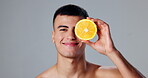 Happy man, skincare and orange for morning routine, organic product and grooming for hygiene or wellness. Male person, fruit and gray background in dermatology, cosmetic and maintenance for vitamin c