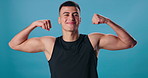 Face, flexing arms and man with power, fitness and progress on blue studio background. Portrait, happy person and model with bicep, strength or wellness with energy, proud or workout with results