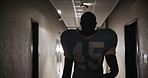 Football player, man and walking through tunnel in stadium for tournament, match and ready for competition. American contact sport, face and professional athlete in cloakroom corridor after half time