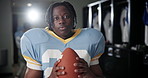 Football player, sport and black man with ball in locker room for match, game preparation and energy for tournament. Professional, athlete and portrait in cloakroom with determination for competition