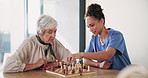 Chess, elderly woman and nurse playing at table for moving, strategy or board game challenge. Solution, teaching and senior person with caregiver for cognitive skills, tactics or retirement home