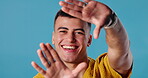 Happy man, hands and face for selfie in studio, live streaming and blue background. Male person, portrait and capture photography for profile picture, social media update and frame for online vlog