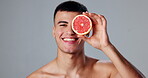 Happy man, skincare and grapefruit for morning routine, natural cosmetics and grooming for hygiene or wellness. Male person, citrus and studio background in dermatology, healthy diet and vitamin c