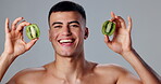 Happy man, skincare and kiwi for morning routine, natural cosmetics and grooming for hygiene or wellness. Male person, exotic fruit and studio background in dermatology, healthy diet and vitamin c