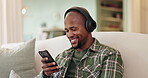 Music, phone and smile with black man on sofa in living room of home for download or streaming. Internet, reading and relax with happy African person in apartment for online radio subscription