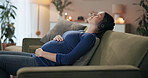 Pregnant, headphones and relax with woman on sofa in living room, home or house with prenatal podcast. Pregnancy, wellness and stomach with young mother with music, streaming or audio in apartment