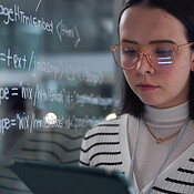 Tablet, woman and coding for solution in office with equation on glass ...