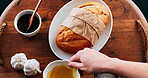 Person, hand and bread with ingredients for breakfast, serving or meal on wooden table above. Top view of whole wheat snack or chef with tasty toppings, butter or salt for lunch, dinner or light dish