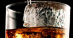 Glass, ice and pour rum in studio for enjoyment, refreshing and cold beverage. Frozen cube, tumbler and whiskey flow on black background with liquor, brandy and aesthetic for testing in distillery