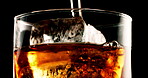 Glass, ice cube or pour liquid in studio for enjoyment, refreshing or cold beverage. Frozen block, tumbler or whiskey flow on black background with liquor, rum or aesthetic for testing in distillery